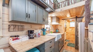 Eine kleine Küche mit Holzausstattung, einem Spülbecken und einem Kühlschrank.