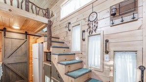 Ein Holzinnenraum mit Treppe, Kühlschrank und Traumfänger an der Wand.