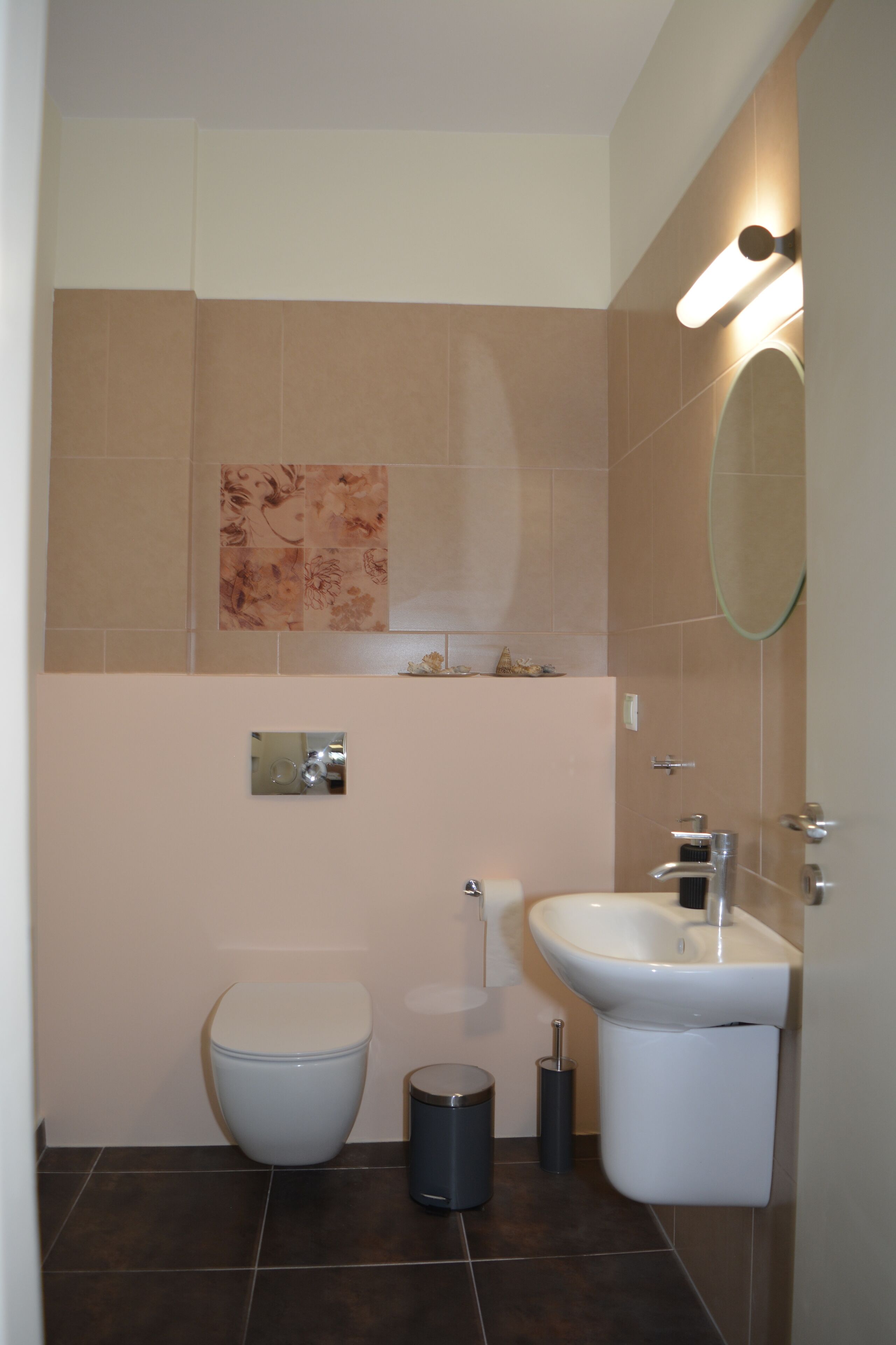 Ein modernes Badezimmer mit Toilette, Waschbecken und Spiegel.