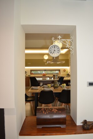 Un coin repas avec une table en bois, des chaises, une horloge et un vase rempli de fleurs.