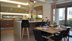 Cocina moderna con una isla grande, sillas de madera y una mesa de comedor preparada para seis personas, con platos, vasos y cubiertos.