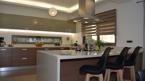 Una cocina moderna con una isla grande, armarios de madera y estufa integrada.