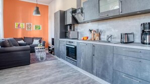 A modern kitchen with grey cabinets, a built-in oven, and a coffee maker.