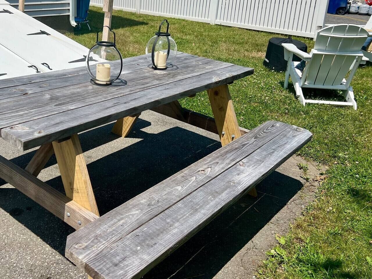Une table de pique-nique en bois avec des bancs, une lanterne et une bougie.