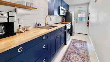 A modern kitchen with dark blue cabinets, a wooden countertop, a built-in oven, and a stainless steel refrigerator.