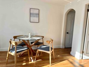 Comedor con una mesa redonda de vidrio y cuatro sillas de madera con asientos acolchados.