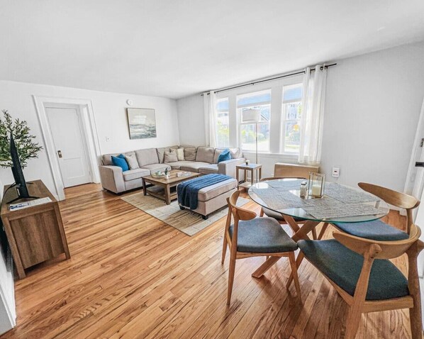 A modern living room with a sofa, coffee table, and dining table with chairs.