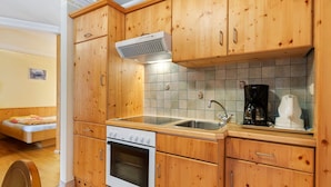 Una cocina con gabinetes de madera, estufa, lavamanos y cafetera.
