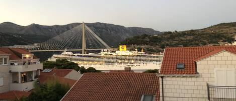 A cruise ship docked near a bridge with mountains in the background.