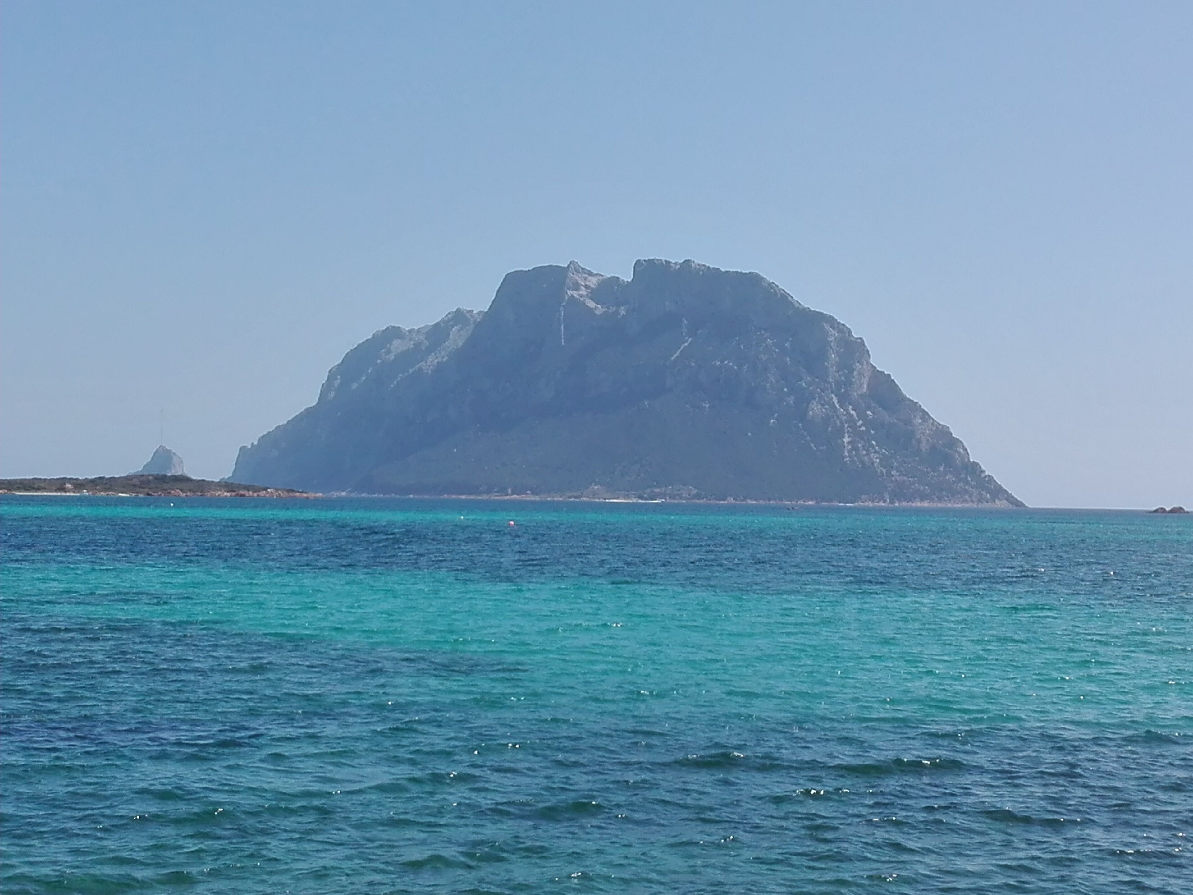 Une grande île rocheuse offrant une vue dégagée sur la mer turquoise, qui s’étend devant elle.