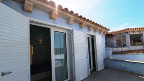 A building with a tiled roof, a balcony, and a sliding glass door. - Three-room apartment Le Maree 8 with sea view (Cannigione)