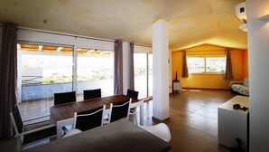 A modern living room with a dining area, large windows, and a view of the outdoors. - Three-room apartment Le Maree 8 with sea view (Cannigione)
