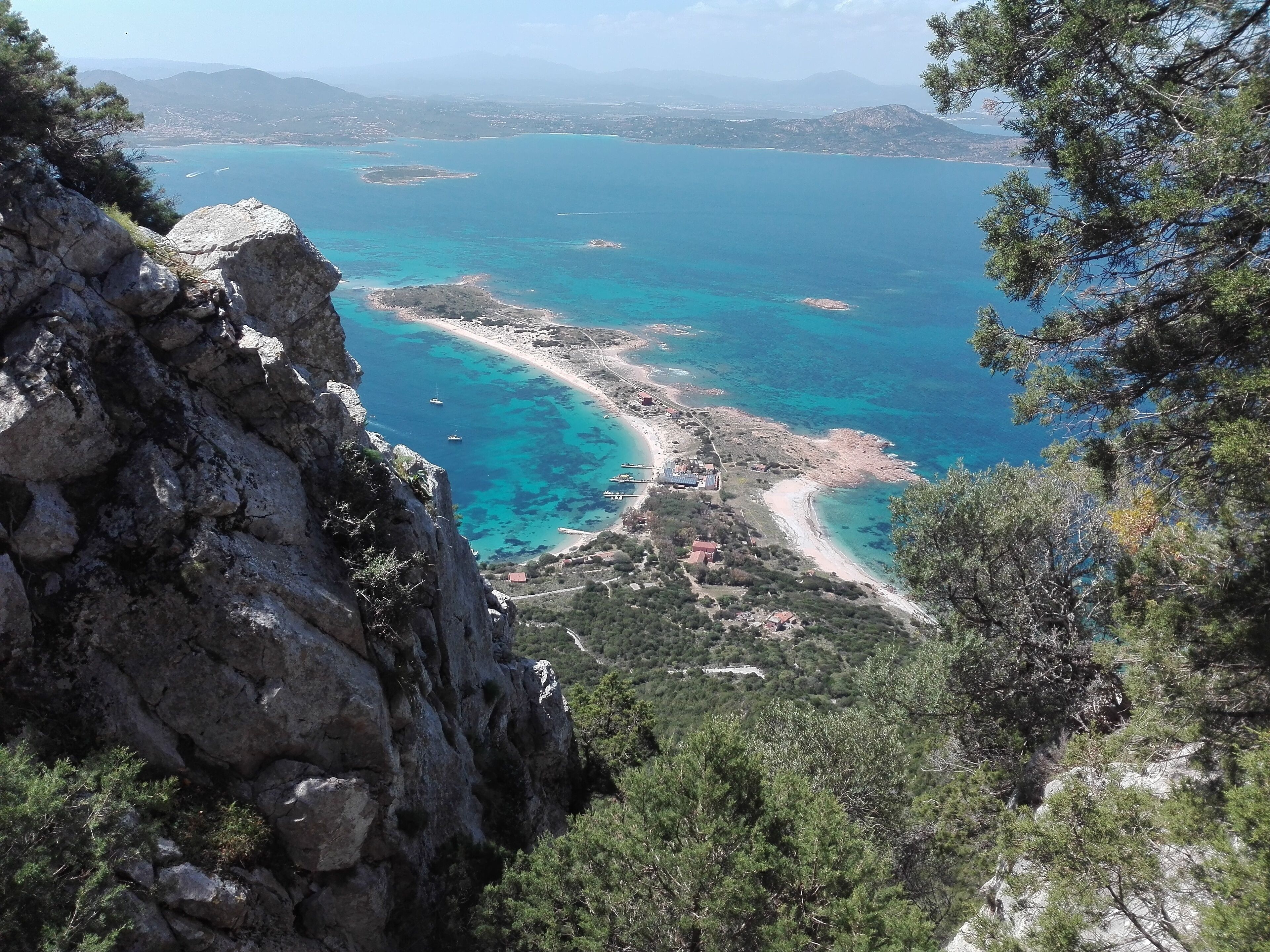 A coastal landscape with rocky terrain and a clear view of turquoise waters.