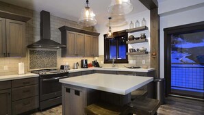 A modern kitchen with a large island, stainless steel appliances, and wooden cabinetry. - Crested Mtn. North L9 (Crested Butte)