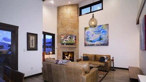 A living room with a fireplace, a television, and a large abstract painting. - Crested Mtn. North L9 (Crested Butte)