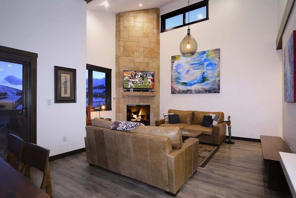 A living room with a fireplace, a television, and a large abstract painting.