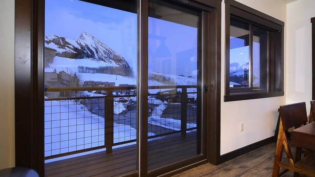 A room with a view of a snowy mountain landscape through large sliding glass doors. - Crested Mtn. North L9 (Crested Butte)