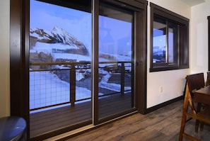 A room with a view of a snowy mountain landscape through large sliding glass doors.