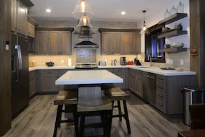A modern kitchen with wooden cabinets, a central island, and pendant lighting.