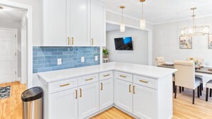 A modern kitchen with white cabinets, a blue backsplash, and pendant lighting. - Pelican Retreat ~ Screened-in Porch ~ Outdoor Shower ~ Large Back Yard ~ King (Wilmington)