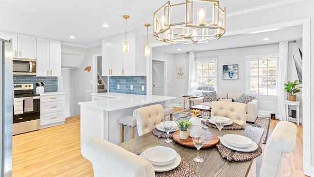 A modern kitchen with white cabinetry, a central island, and pendant lighting. - Pelican Retreat ~ Screened-in Porch ~ Outdoor Shower ~ Large Back Yard ~ King (Wilmington)