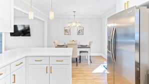 A modern kitchen with white cabinetry, a stainless steel refrigerator, and pendant lighting. - Pelican Retreat ~ Screened-in Porch ~ Outdoor Shower ~ Large Back Yard ~ King (Wilmington)