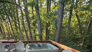 A deck with Adirondack chairs, a hot tub, and a fire feature. - The Monarch: A Pinehurst Retreat (Carthage)
