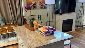 A kitchen island with a granite countertop, a built-in oven, and a grey cabinet. - The Monarch: A Pinehurst Retreat (Carthage)