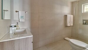 Ein modernes Badezimmer mit einem großen Spiegel, einem Waschbecken und einer Toilette.