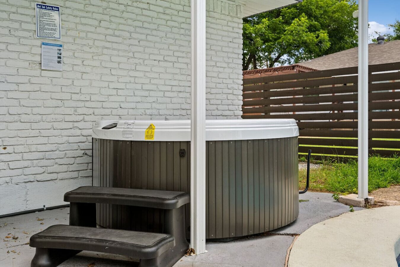 Een hottub met treden en een veiligheidsteken op een witte bakstenen muur.