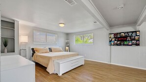 A bedroom with a bed, bedside tables, a wall-mounted TV, and a window.