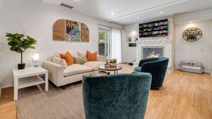 A modern living room with a white sofa, teal armchairs, a coffee table, and a fireplace.