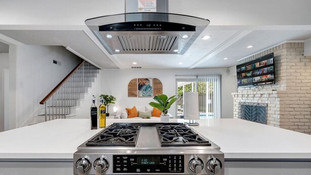 A modern kitchen with a central island, stainless steel appliances, and a built-in range hood.