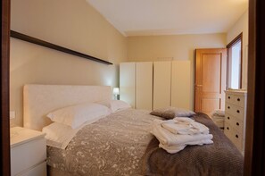 A bedroom with a bed, a nightstand, a dresser, and a wardrobe.