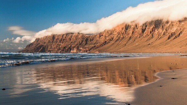 Una playa con un acantilado rocoso y olas.