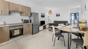 Una cocina moderna con armarios de madera, horno empotrado y comedor con mesa dispuesta para cuatro.