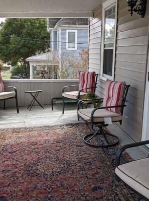 Relax on the covered porch with a seating area featuring two chairs and a small table.