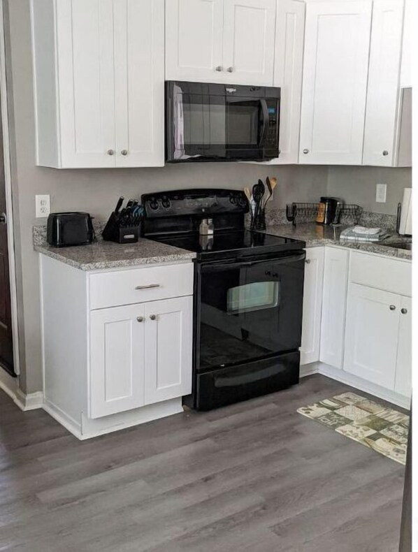 Effortlessly prepare meals in this well-equipped kitchen with a black stove, microwave, and ample countertop space.