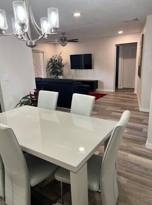 Relax in this stylish living room with a dining table, comfortable seating, and a flat-screen TV.