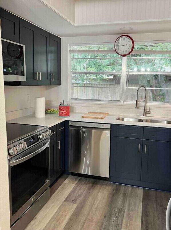 Enjoy cooking in this well-equipped kitchen with an oven, stainless steel appliances, and a large window offering a view of the surrounding greenery.