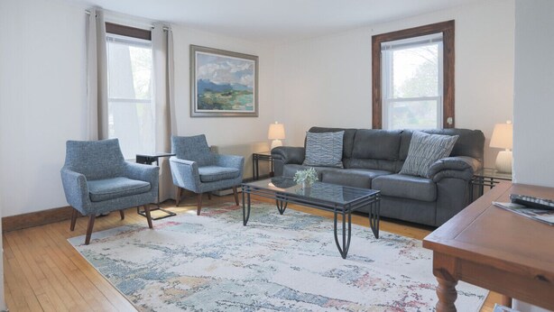 Un salon comprenant un canapé, deux fauteuils, une table basse et un tapis.