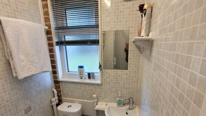 Un baño pequeño con inodoro, lavamanos y ventana.