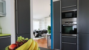 Una cocina moderna con microondas, horno y una cesta de fruta en la encimera.