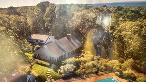 Ett stort hus med en swimmingpool, omgivet av tät vegetation och med utsikt över havet.