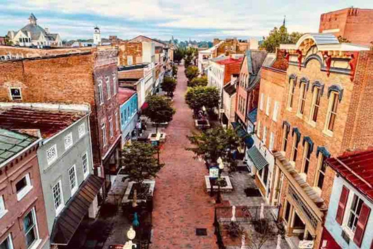 A street view with buildings, a paved walkway, and a clear sky.