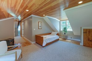 Un dormitorio con techo inclinado, una cama, un radiador y una ventana.