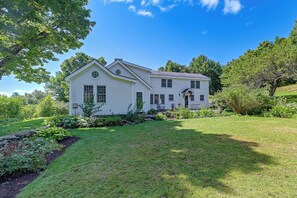 A two-story white house with a well-maintained lawn and garden.