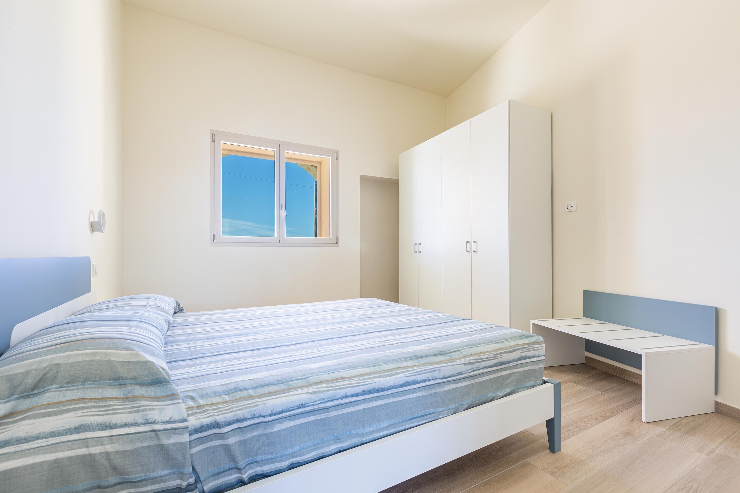 A bedroom with a bed, a wardrobe, and a desk.