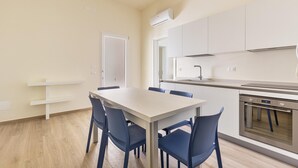 A modern kitchen with white cabinets, a built-in oven, and a dining area with a table and chairs. - 3330 Appartamento Gemma Marina PT by Barbarhouse (Morciano di Leuca)