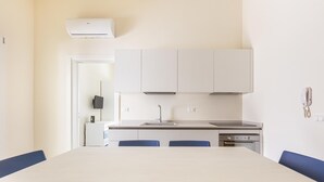 A modern kitchen with white cabinets, a built-in oven, and a large table with blue chairs. - 3330 Appartamento Gemma Marina PT by Barbarhouse (Morciano di Leuca)